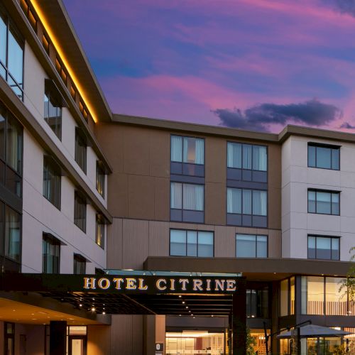 The image shows the exterior of Hotel Citrine during twilight, with a clear sky and modern building architecture.