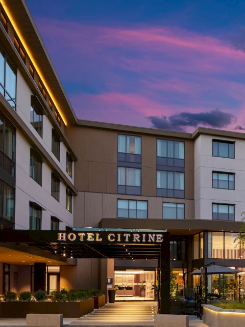 The image shows the exterior of Hotel Citrine during twilight, with a clear sky and modern building architecture.